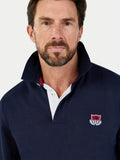 Man wearing a navy blue pullover with a logo on a white background