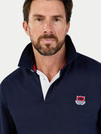 Man wearing a navy blue pullover with a logo on a white background