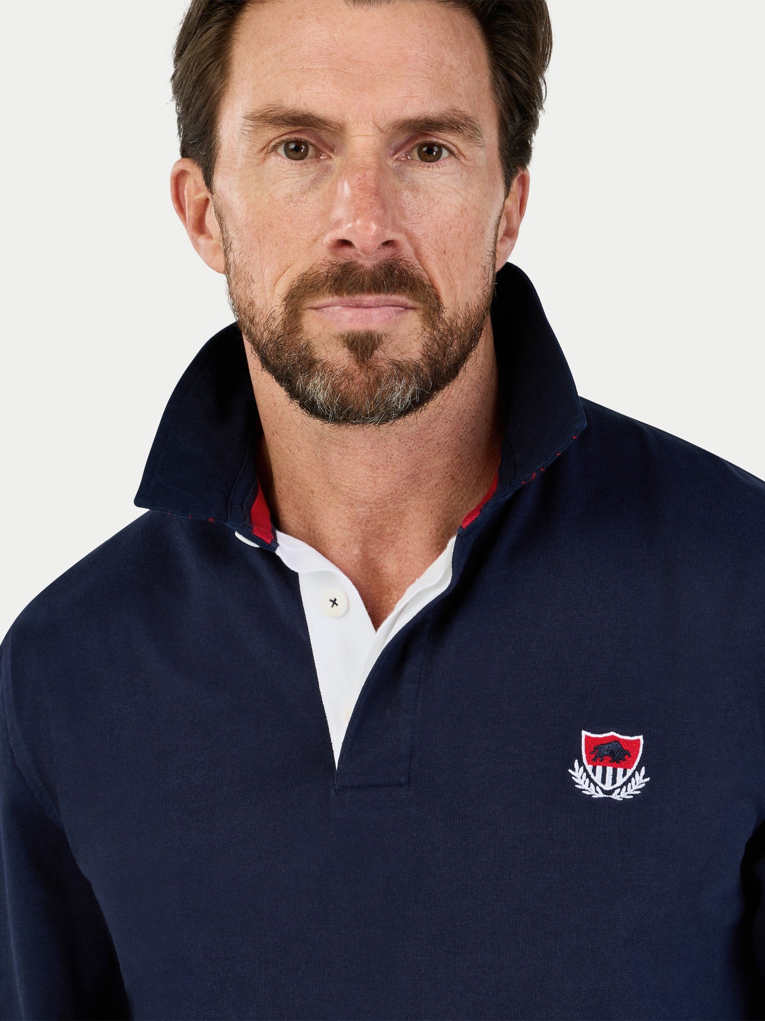 Man wearing a navy blue pullover with a logo on a white background
