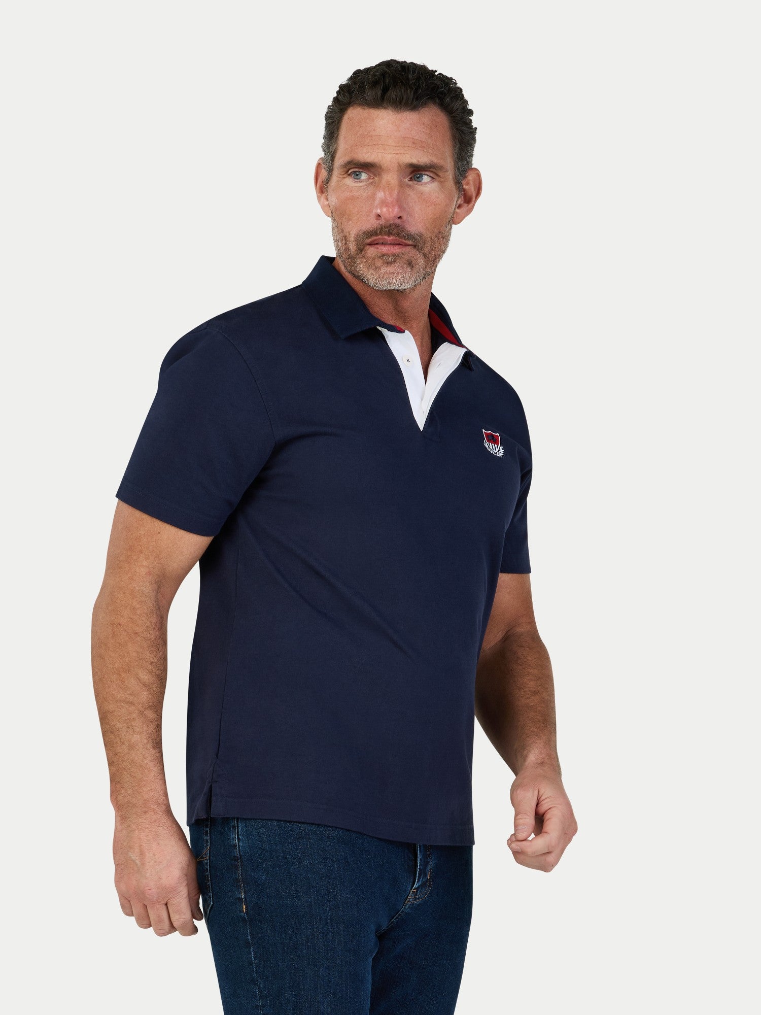 Man wearing navy coloured short sleeve rugby top on a grey background.