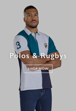 Man in a striped polo shirt and cap adjusting his hat outdoors by a river.