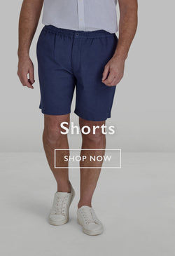 Two men wearing casual shorts and sneakers standing outdoors on a forest path.