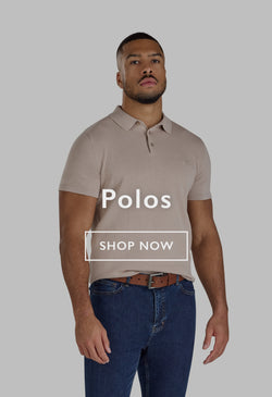 Man in a red polo shirt sitting on a stone wall outdoors, looking to the side.