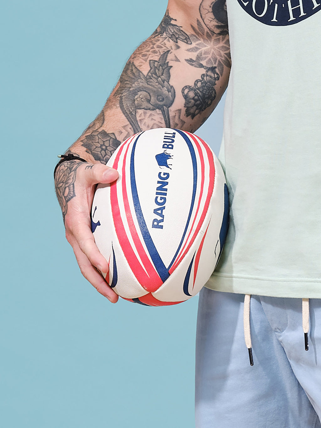 Man holding a Raging Bull rugby ball. 