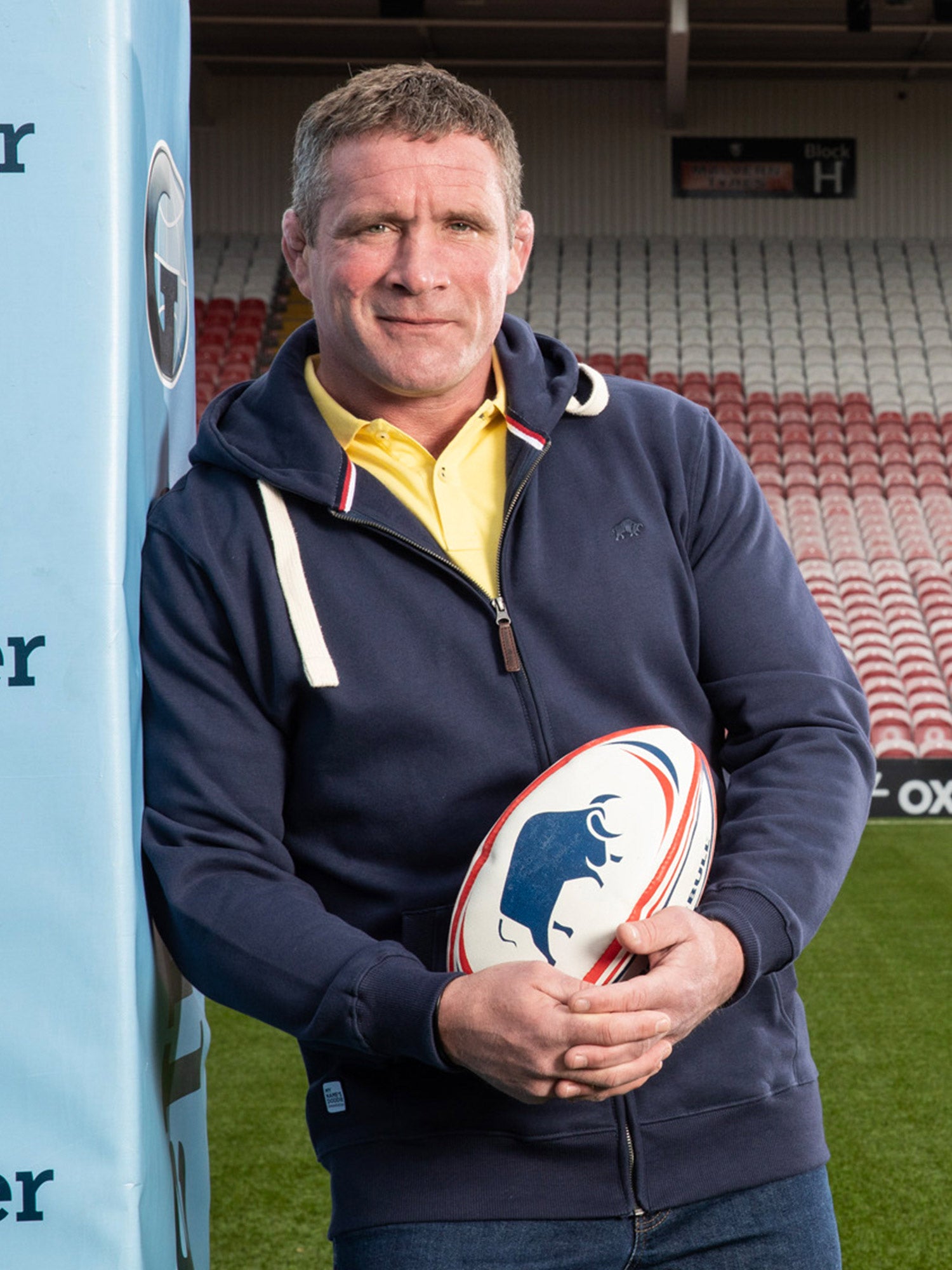 Phil Vickery holding a Raging Bull rugby ball. 