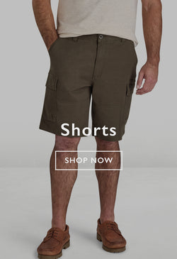 Two men wearing casual shorts and sneakers standing outdoors on a forest path.