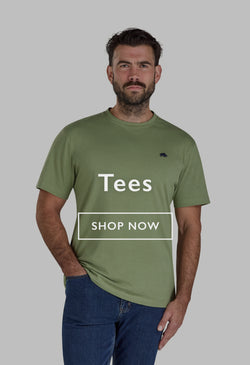 Man in an orange graphic T-shirt and dark trousers standing on outdoor steps, looking down.