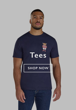 Man in an orange graphic T-shirt and dark trousers standing on outdoor steps, looking down.