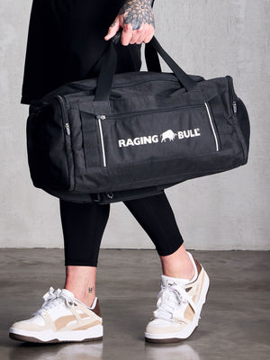 a person carrying a black Raging Bull duffel bag. 