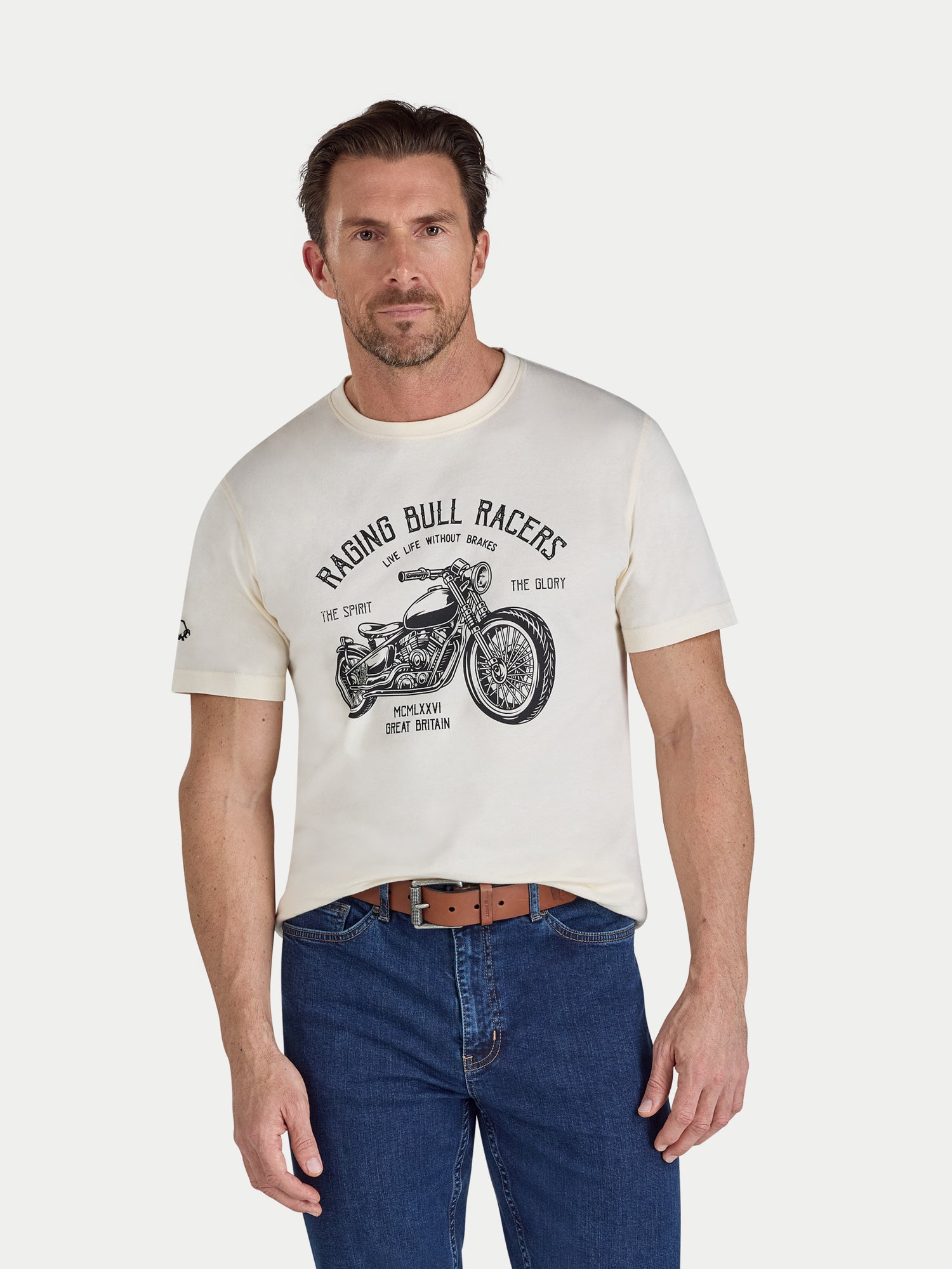 Man wearing a cream t-shirt with a motorcycle graphic and text on a white background