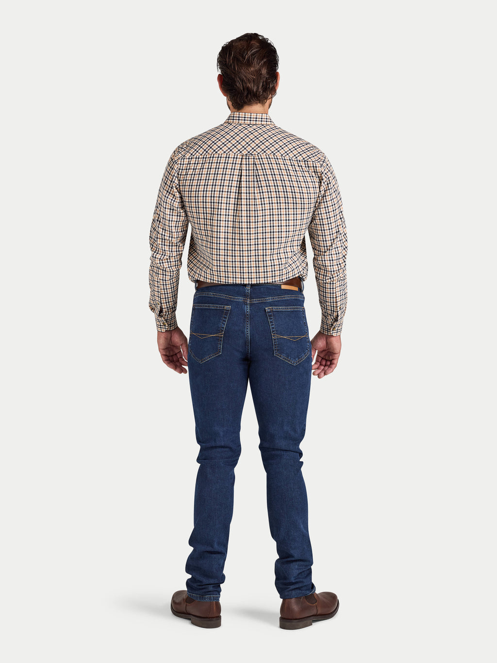 Man wearing a plaid shirt and blue jeans on a white background