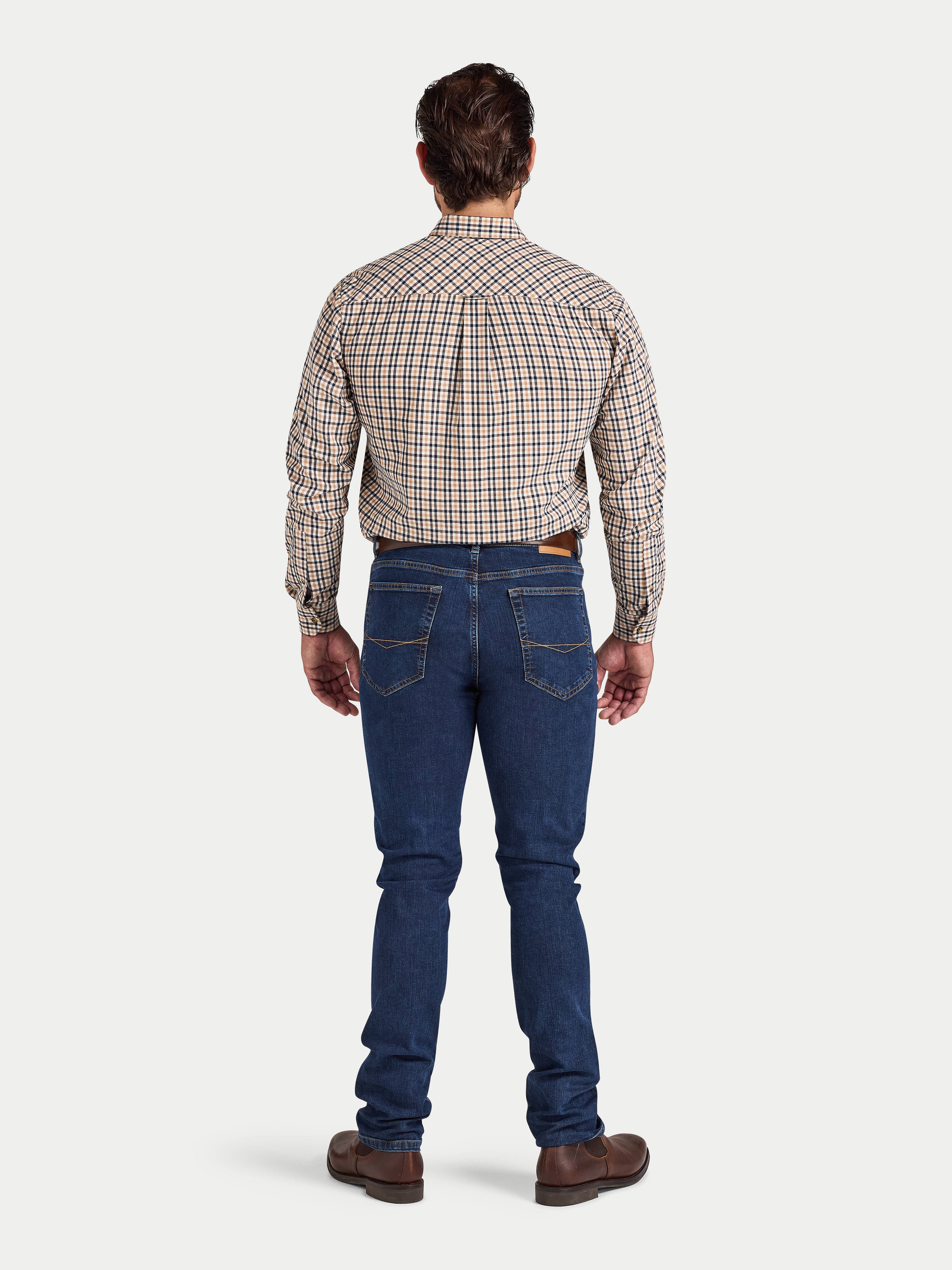 Man wearing a plaid shirt and blue jeans on a white background