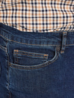 Close-up of blue jeans with a checkered shirt underneath