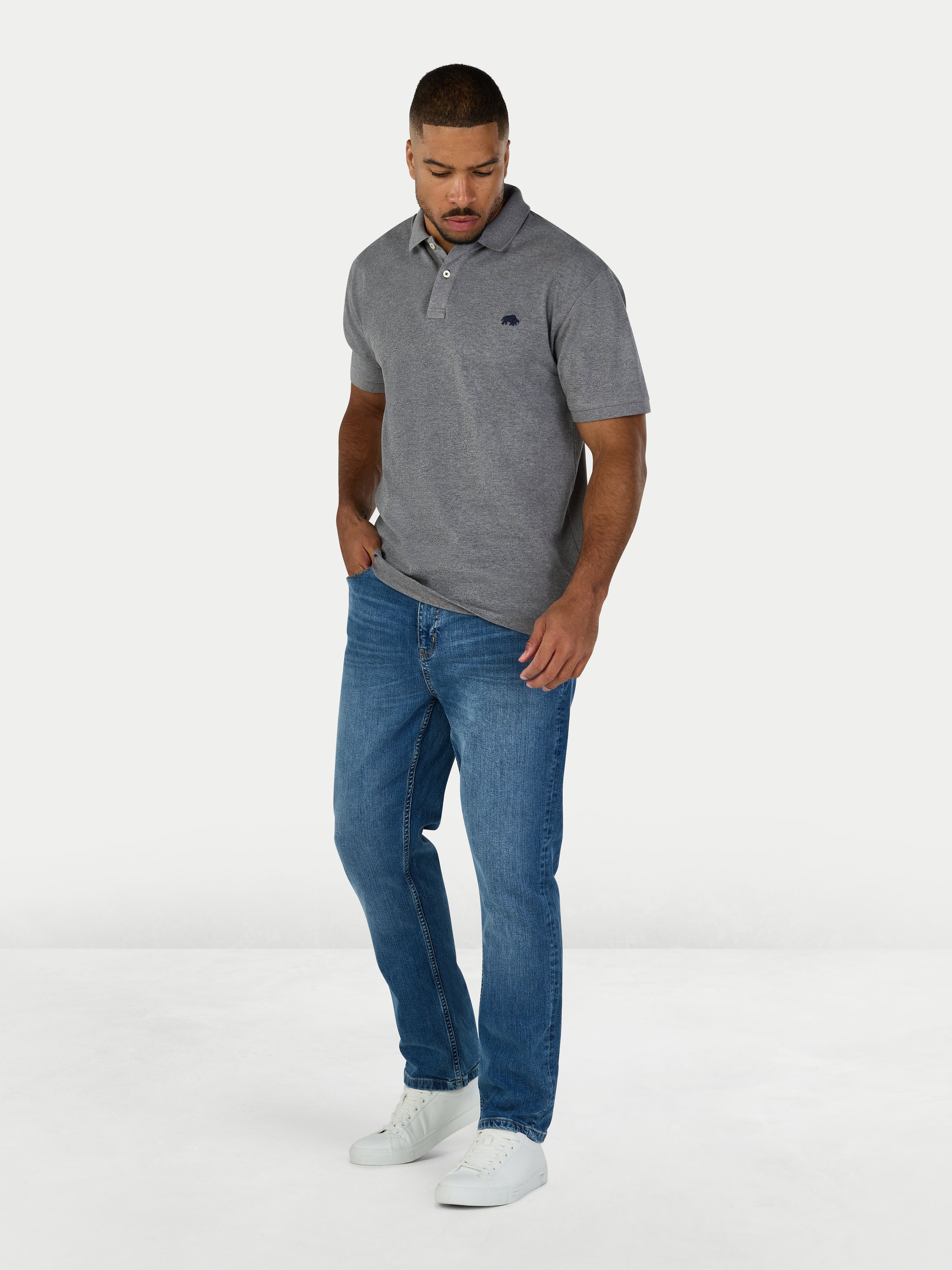 Man wearing a gray polo shirt and blue jeans on a white background