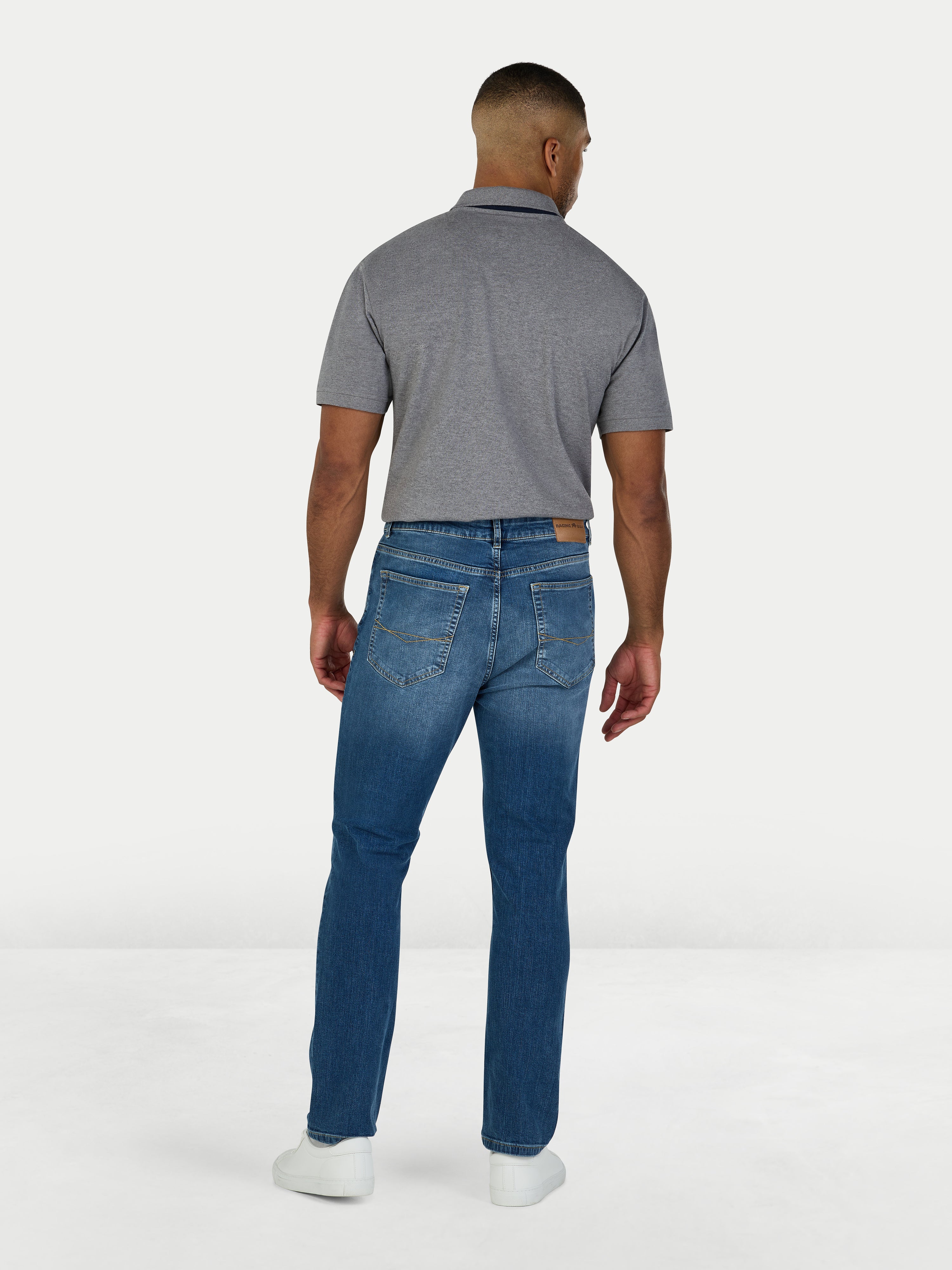 Man wearing a gray polo shirt and blue jeans on a white background