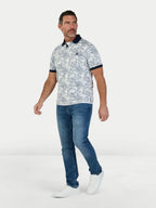 Man wearing a patterned polo shirt and blue jeans on a white background