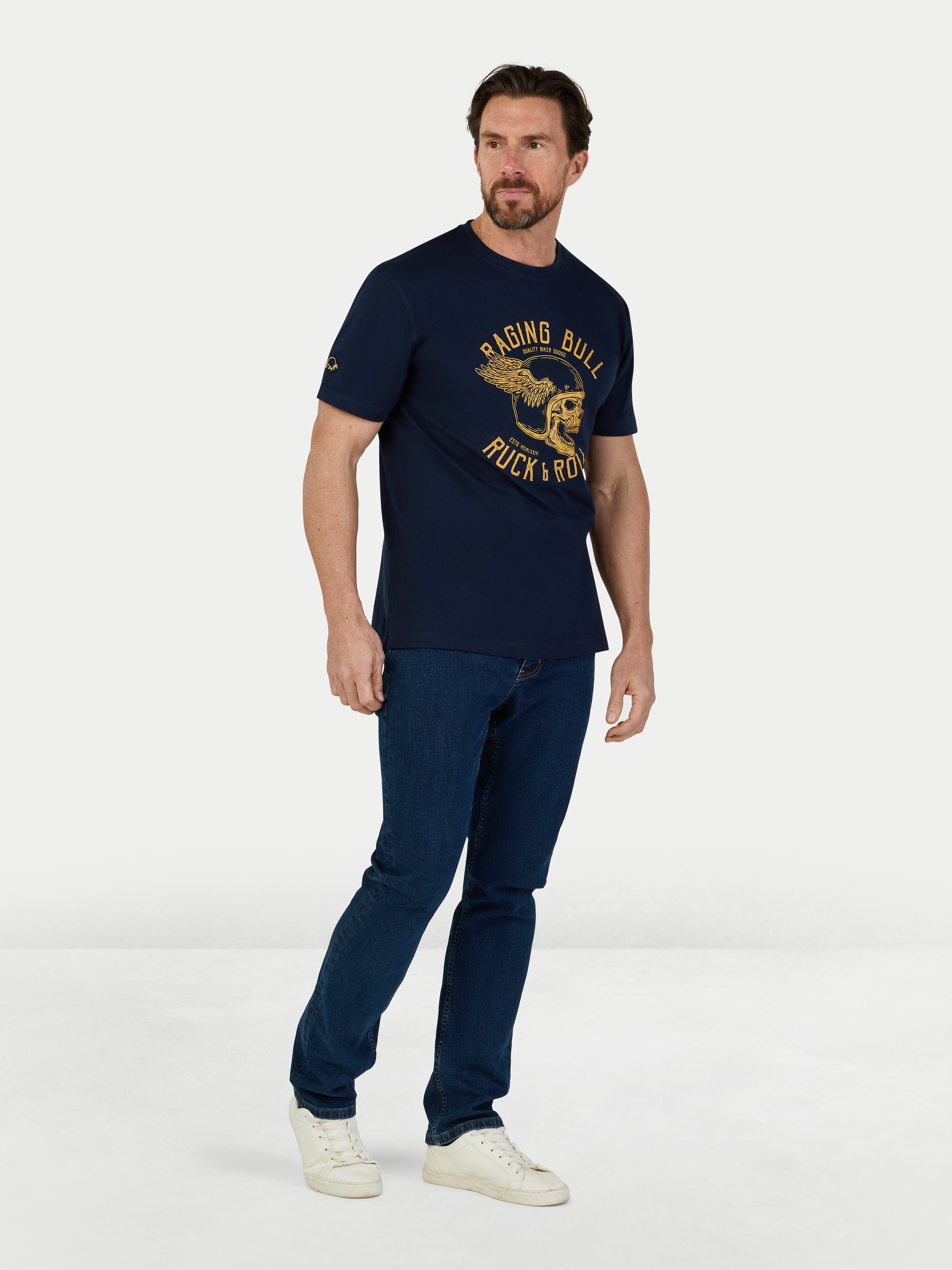 Man wearing a navy blue t-shirt with a logo and text, standing against a white background