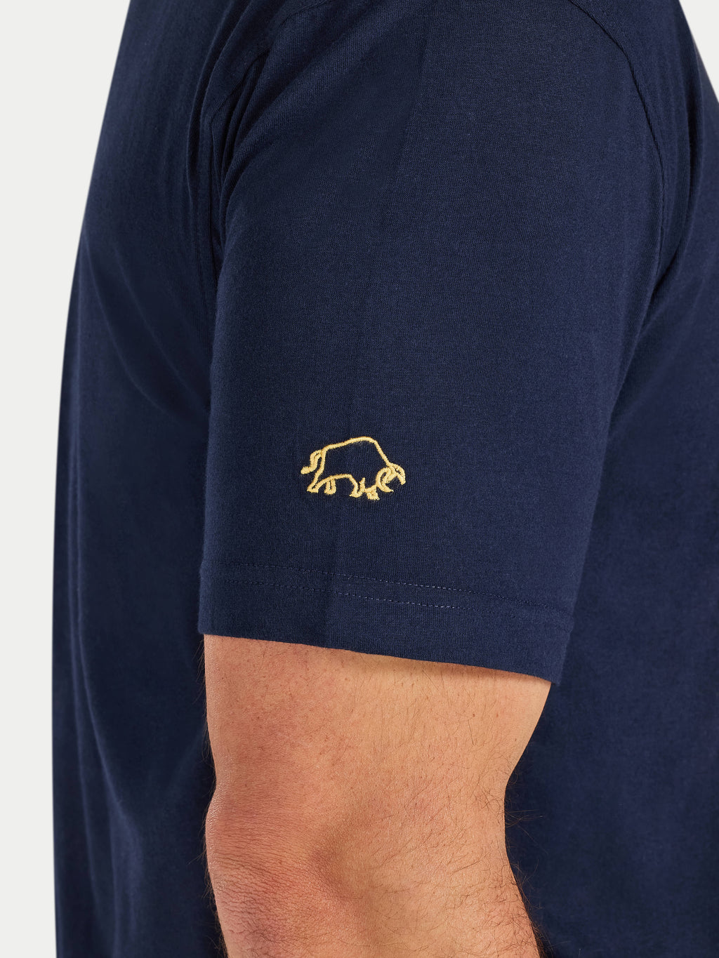 Navy blue t-shirt with a gold logo on the sleeve against a white background