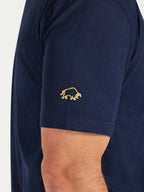 Navy blue t-shirt with a gold logo on the sleeve against a white background