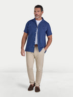 Man wearing Raging Bull Athens Stripe Linen Revere Short Sleeve Shirt in Navy and Classic Chino Trousers in tan, available in sizes S-6XL.