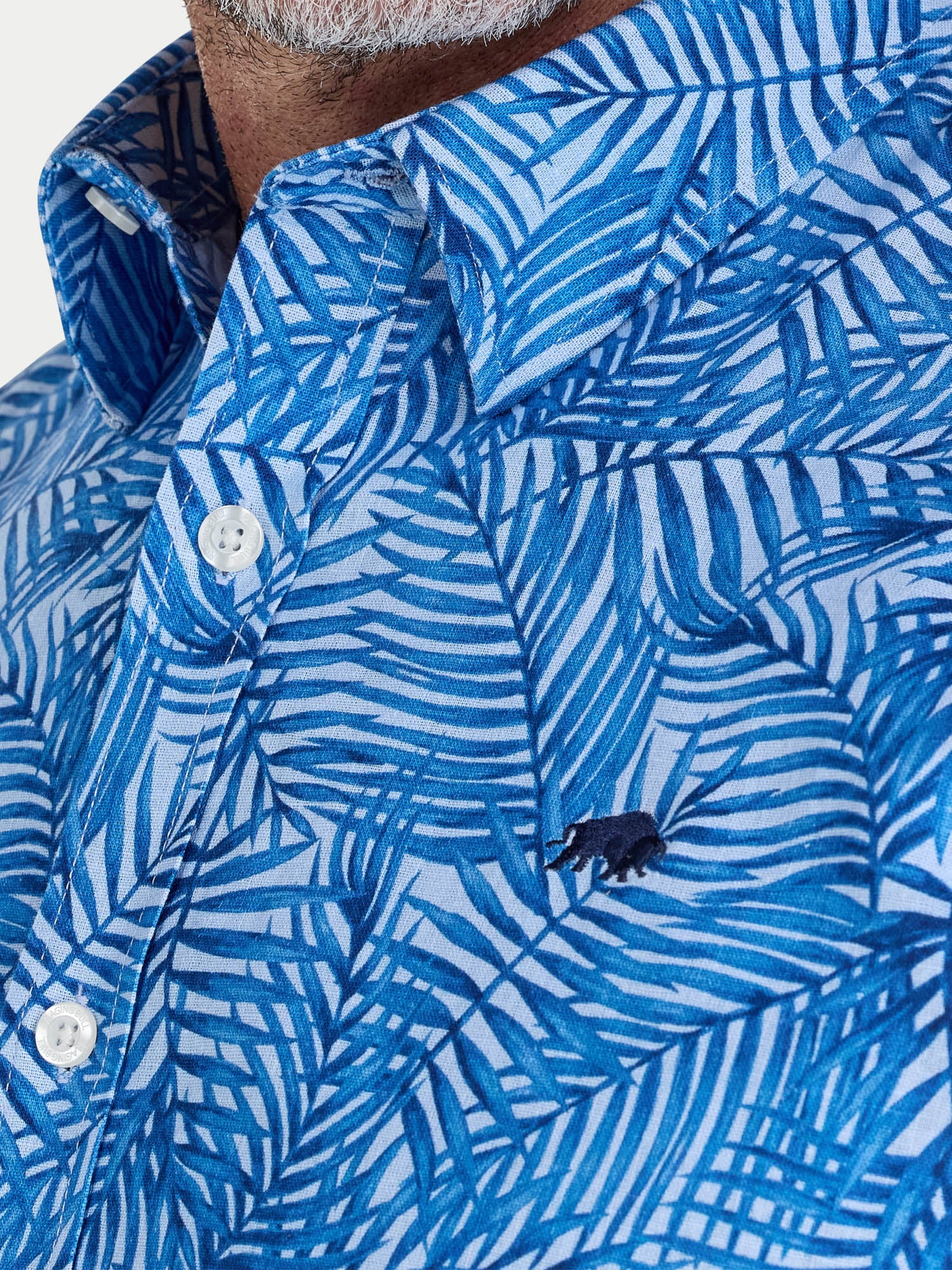 Man wearing Raging Bull Bali Palm Linen Short Sleeve Shirt in Sky Blue, collar and chest detail, available in sizes S-6XL.
