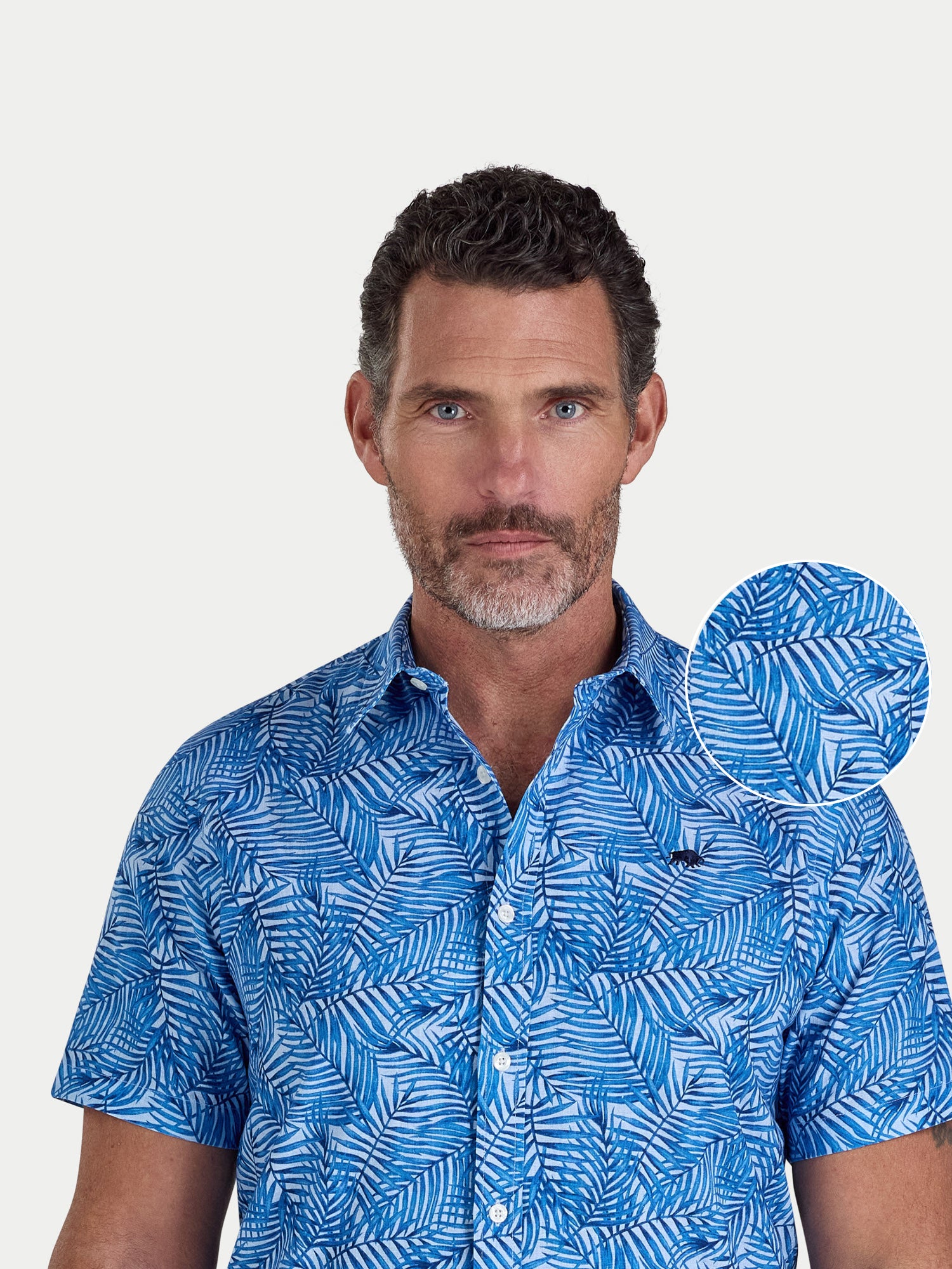 Close-up of a man wearing Raging Bull Bali Palm Linen Short Sleeve Shirt in Sky Blue, available in sizes S-6XL, front detail. 