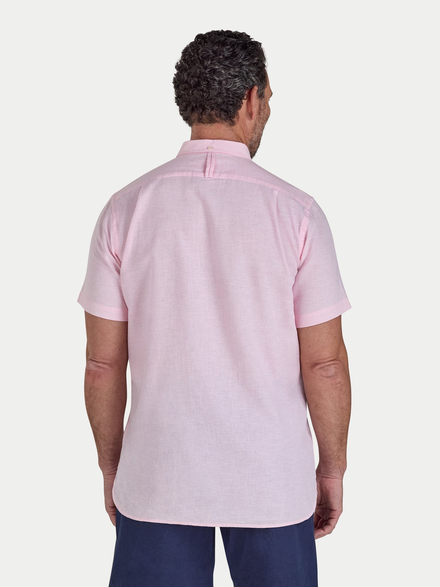 Man wearing a light pink short-sleeve shirt on a white background