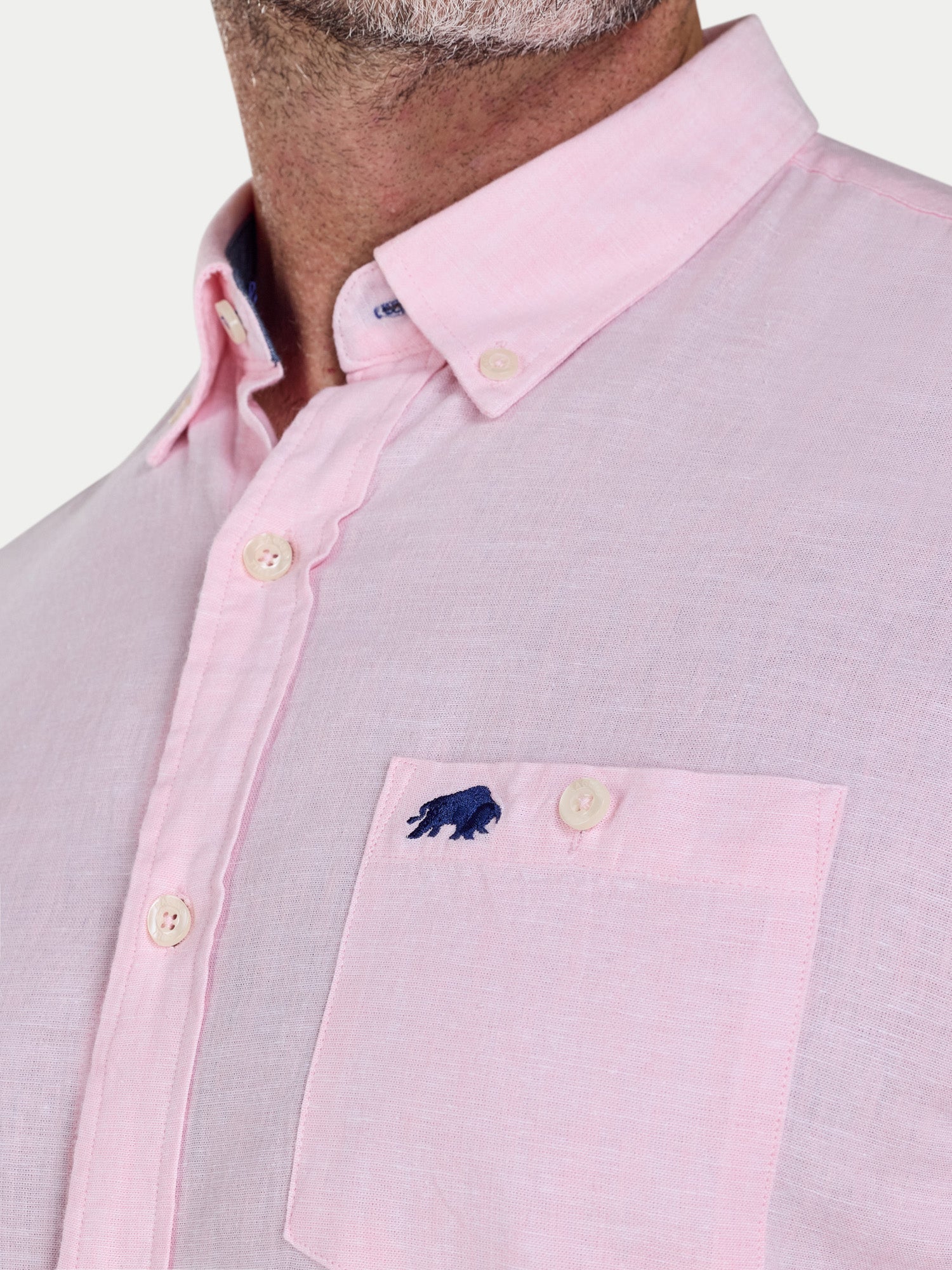 Close-up of a light pink and gray checkered shirt with a pocket and button details.