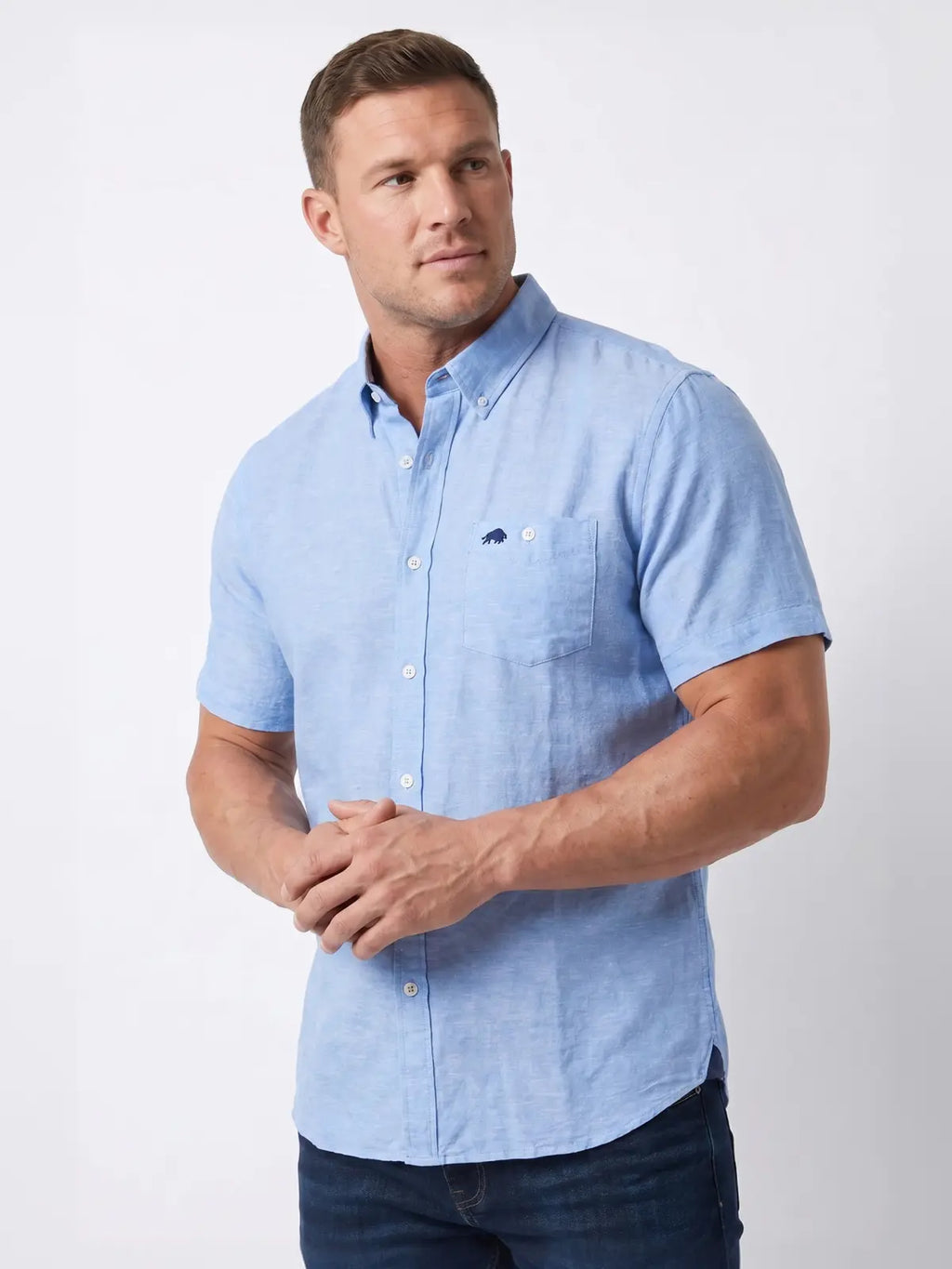 Man wearing Raging Bull short sleeve classic linen shirt in sky blue and jeans, front. 