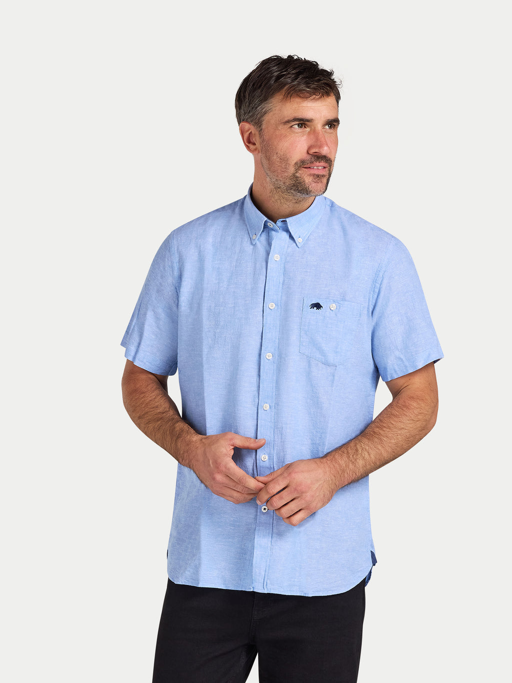 Man wearing a light blue short-sleeve shirt with a logo on a white background
