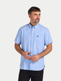 Man wearing a light blue short-sleeve shirt with a logo on a white background