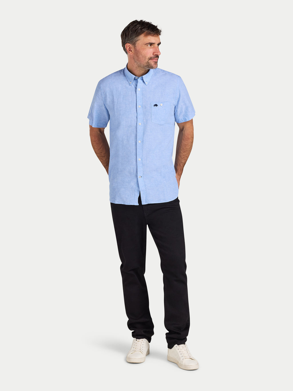 Man wearing a light blue short-sleeve shirt and black pants on a white background