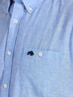 Close-up of a blue shirt with a small logo on the chest pocket.