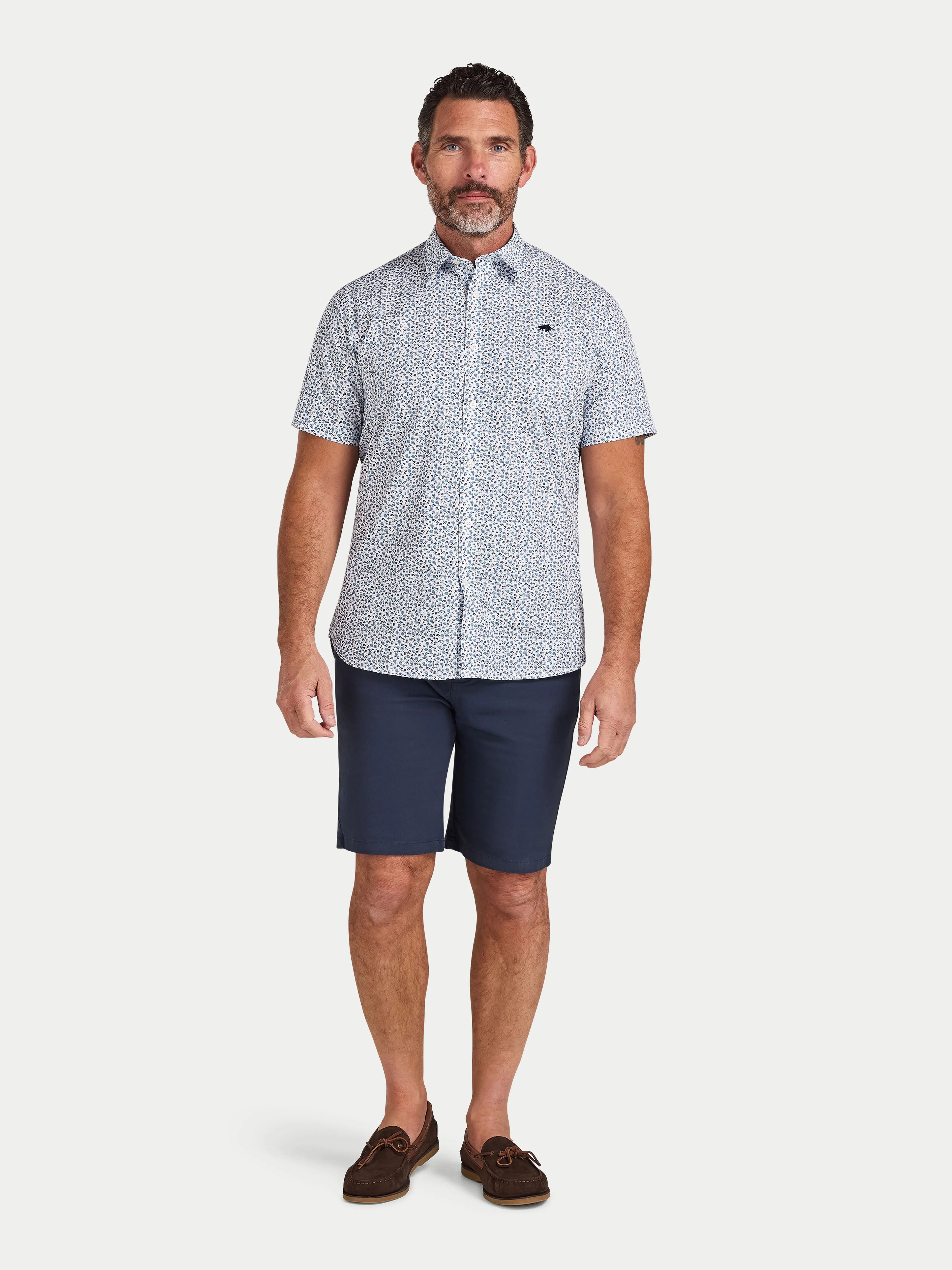 Man wearing Raging Bull Floral Cotton Poplin Short Sleeve Shirt in Sky Blue and Classic Chino Short in navy, available in sizes S-6XL.