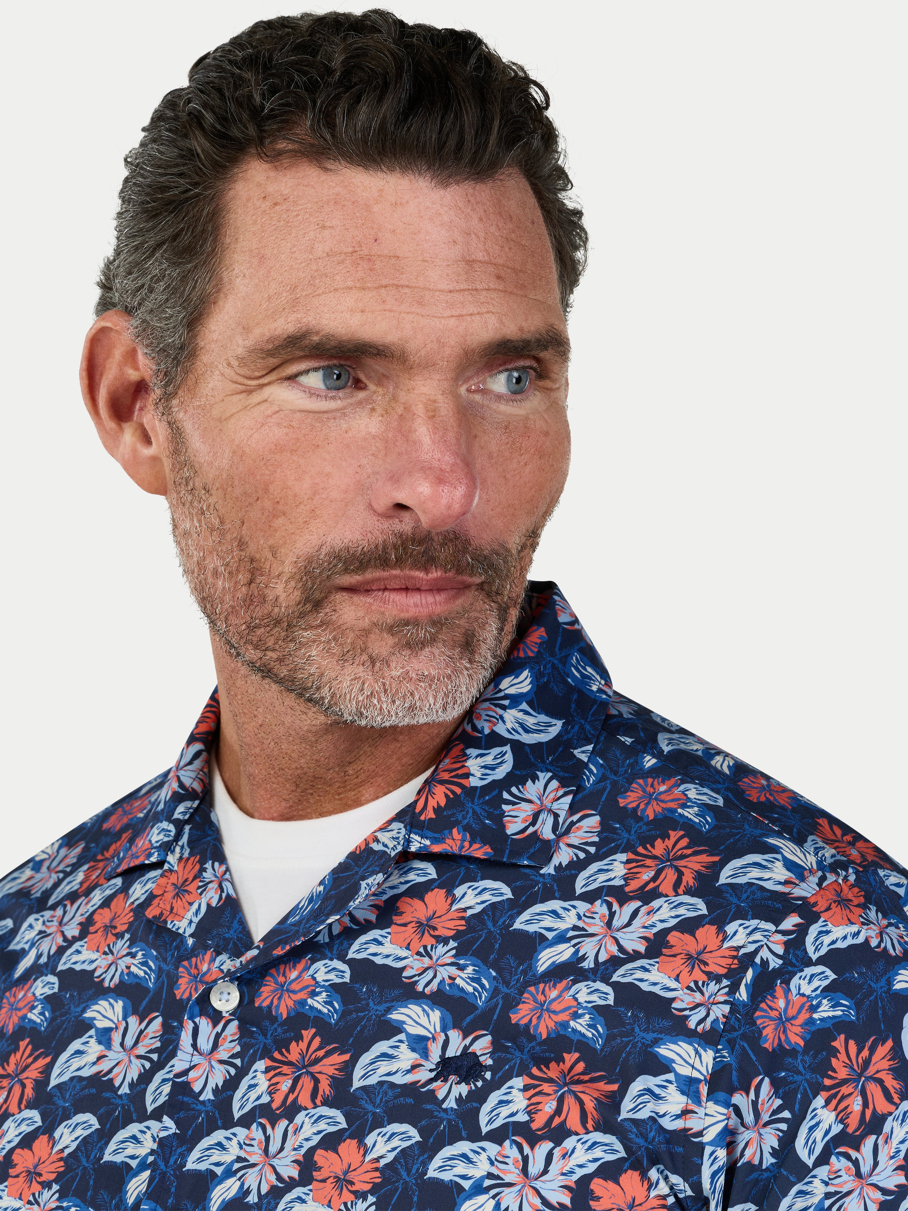 Man wearing a floral patterned shirt against a white background