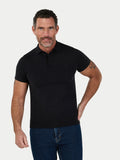 Man wearing a black polo shirt and blue jeans on a white background