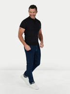 Man wearing a black polo shirt and blue jeans on a white background