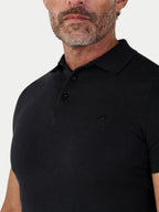 Man wearing a black polo shirt against a light gray background