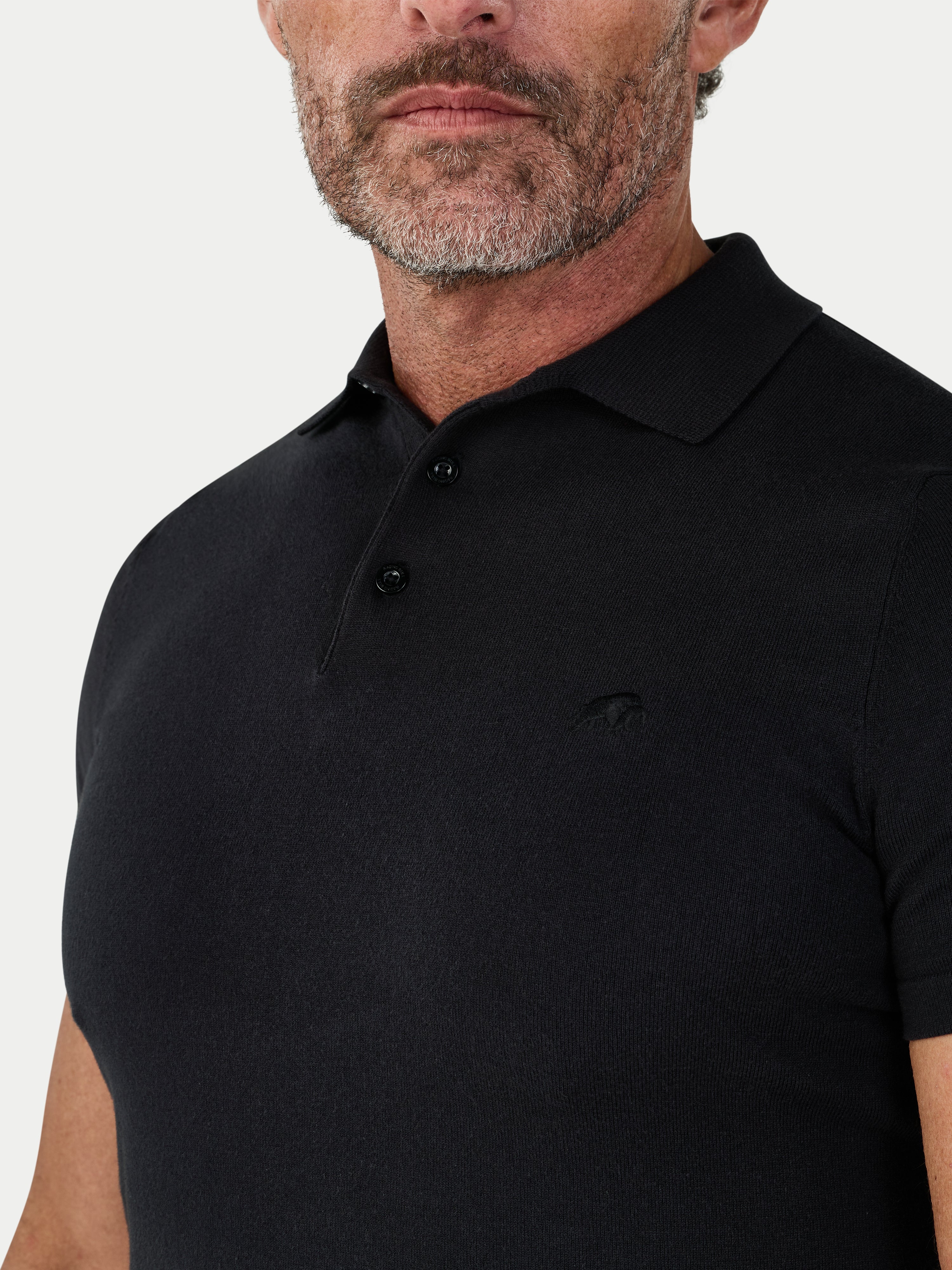Man wearing a black polo shirt against a light gray background
