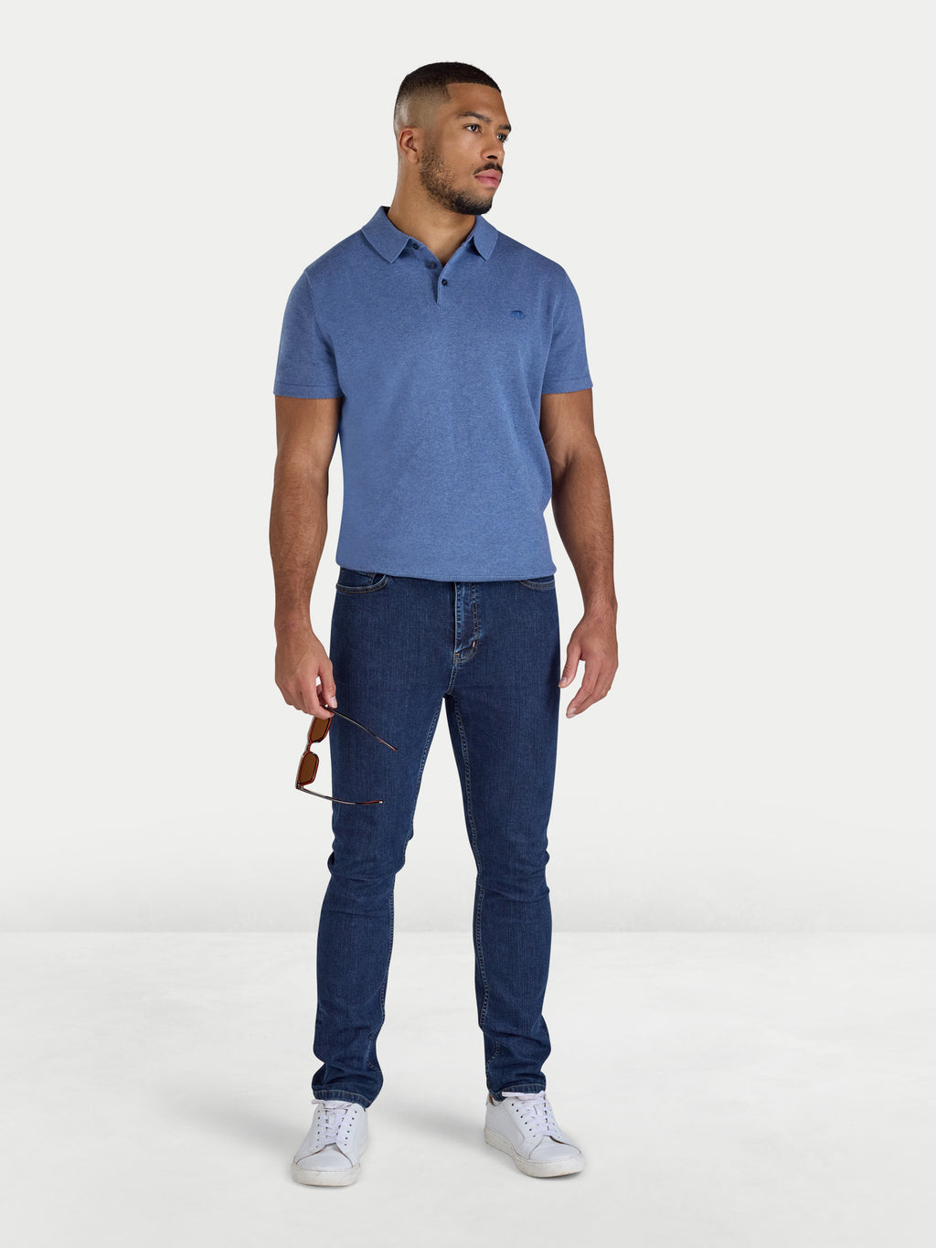 Man wearing a blue polo shirt and jeans on a white background