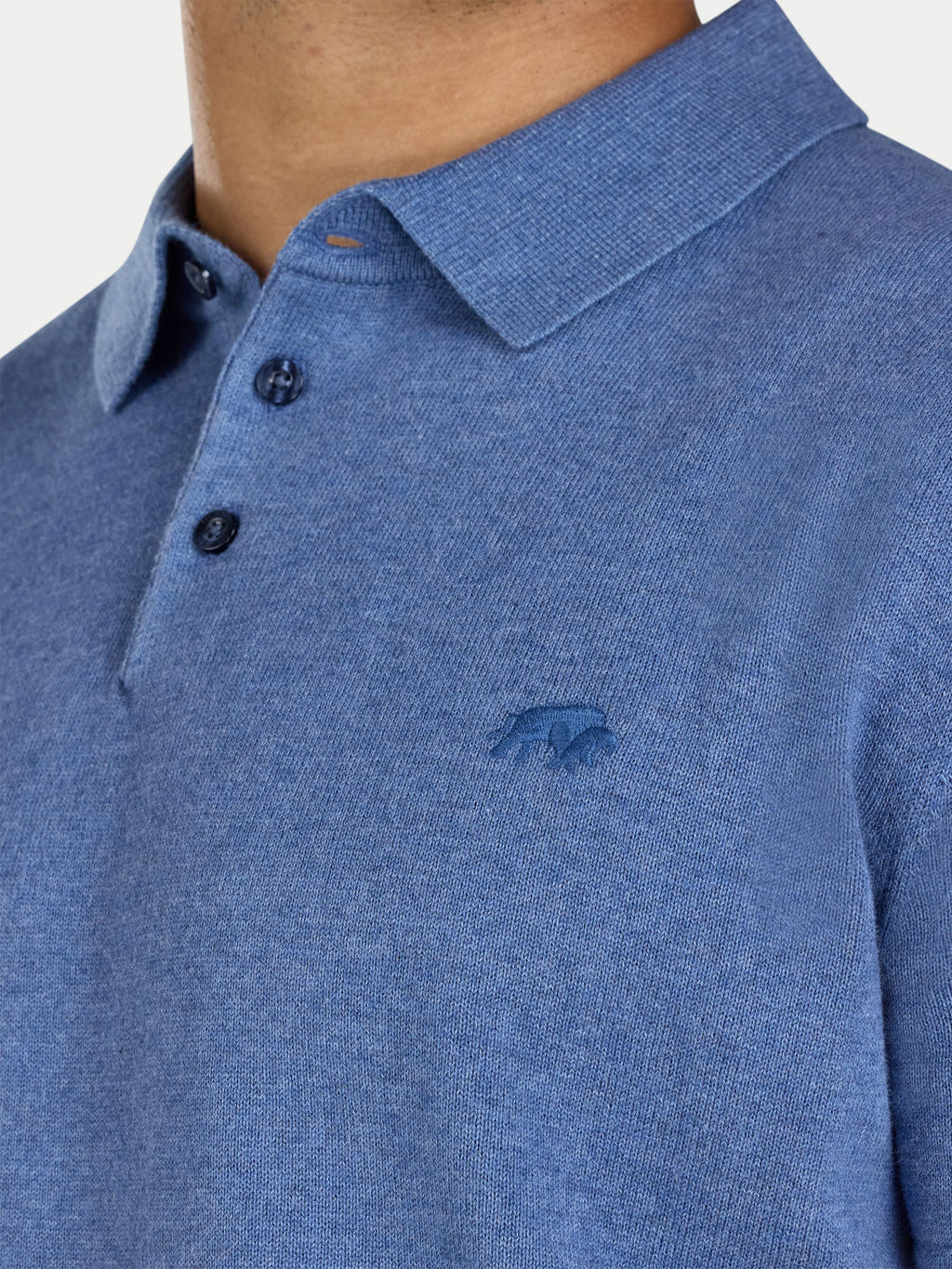 Close-up of a blue polo shirt with a logo on a white background