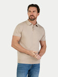 Man wearing a beige polo shirt and blue jeans on a white background