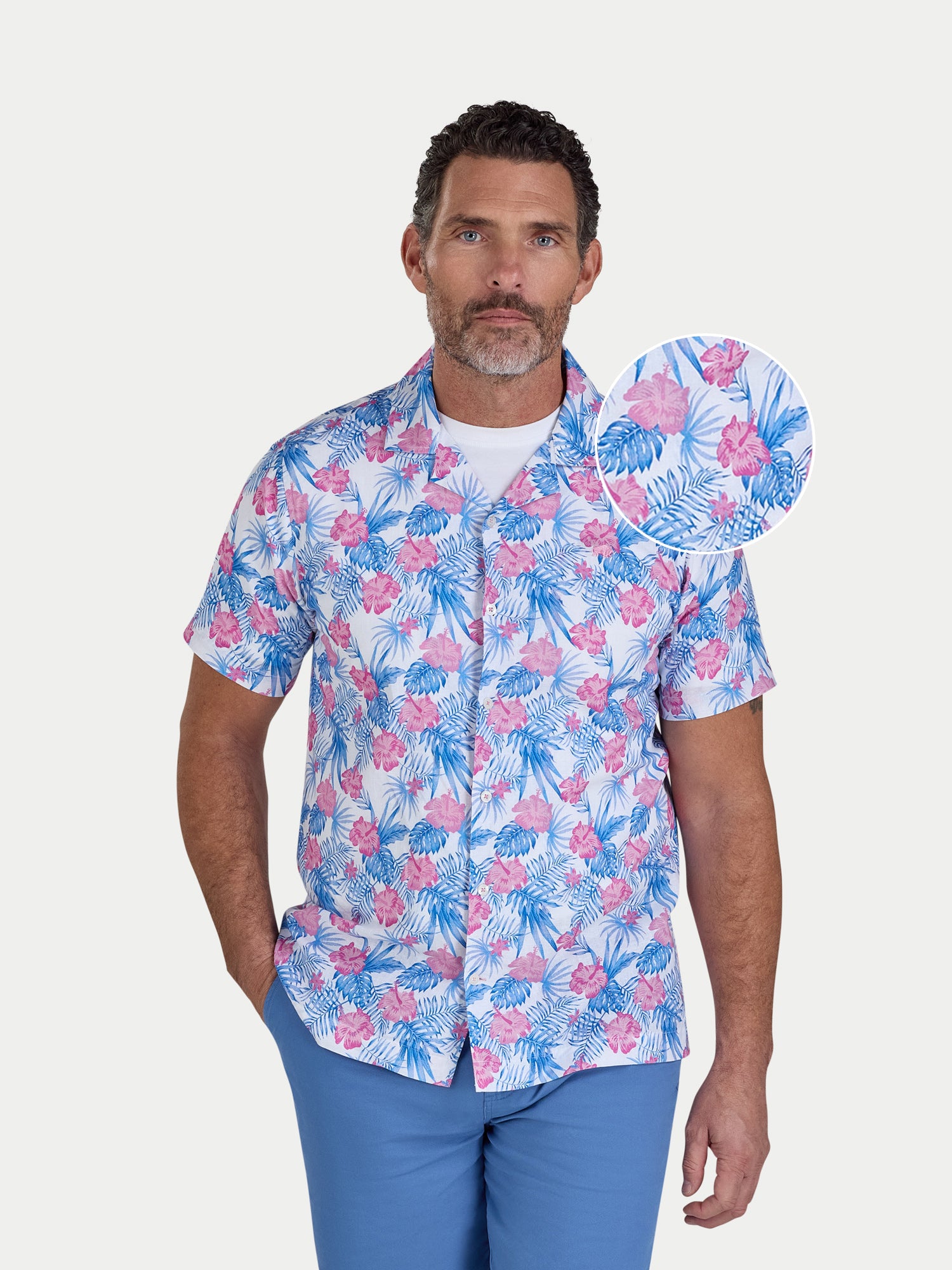 Man wearing a colorful floral shirt with a matching hat on a white background