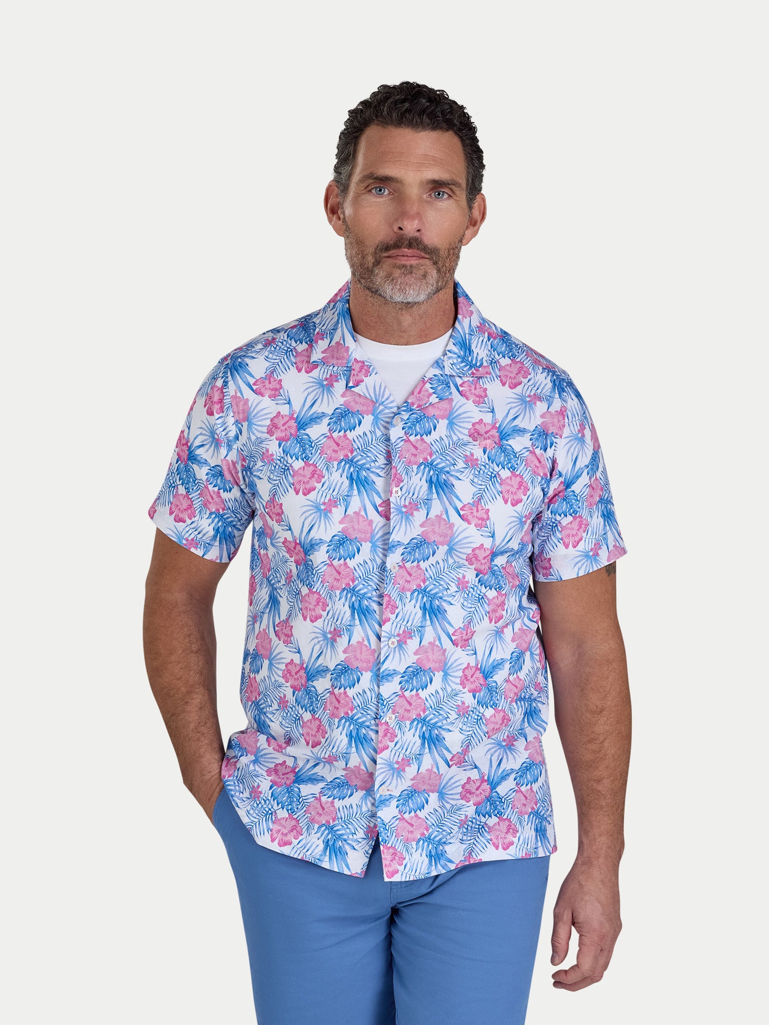 Man wearing a colorful floral shirt with a white background