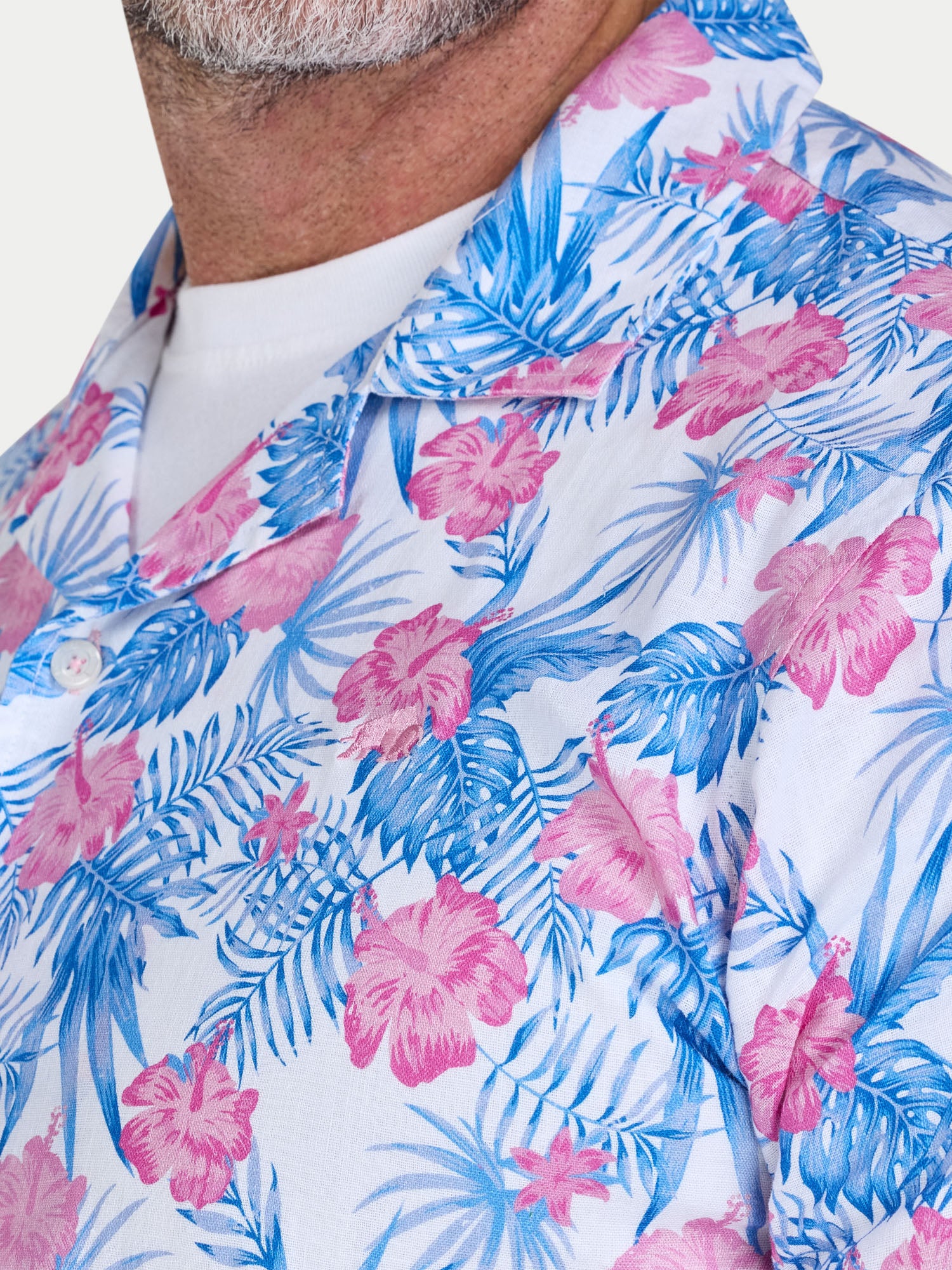 Close-up of a person wearing a tropical floral patterned shirt with pink and blue colors.