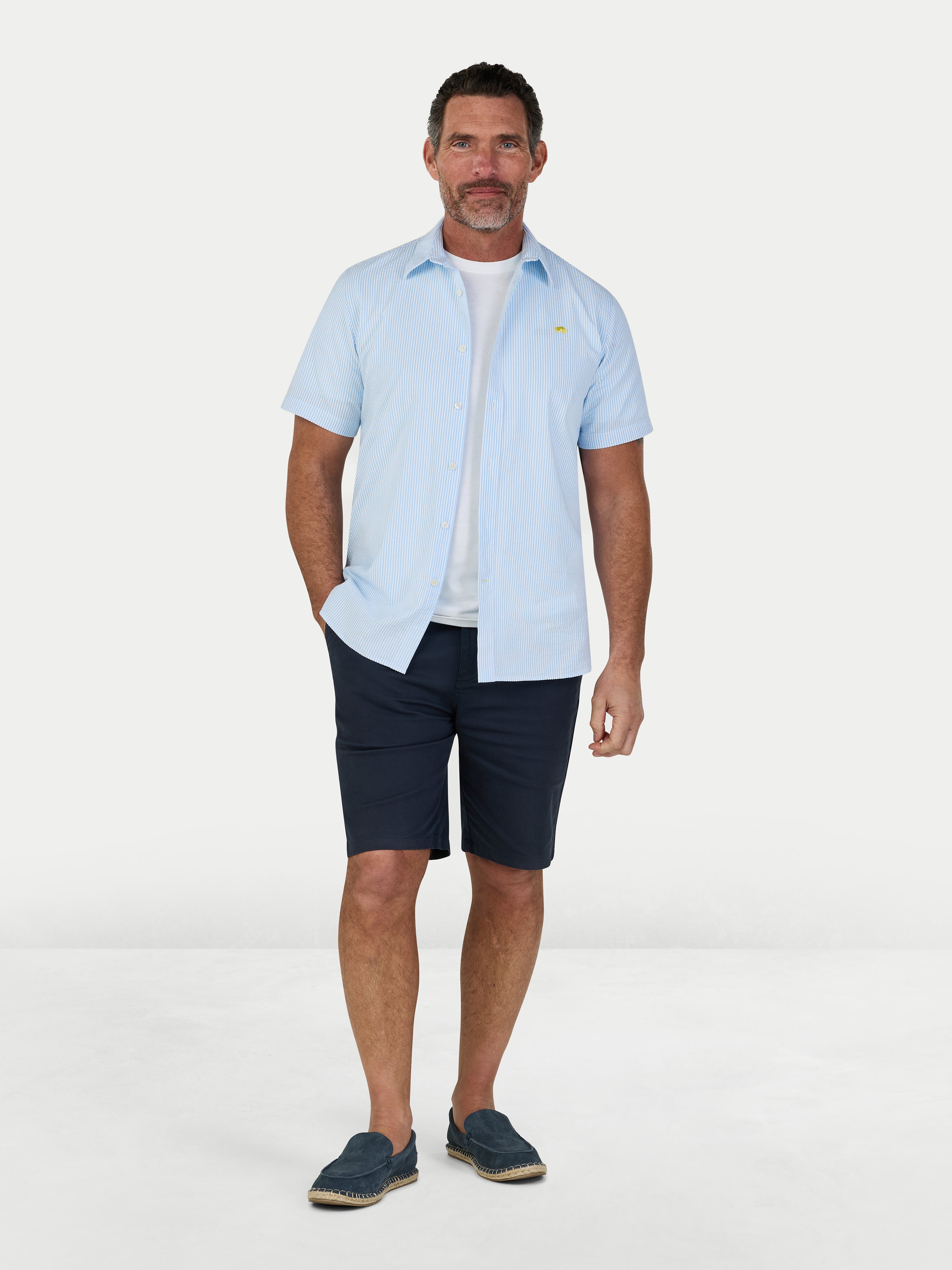 Man wearing Raging Bull Orleans Seersucker Stripe Short Sleeve Shirt in Sky Blue and Classic Chino Shorts in Navy, available in sizes S-6XL.