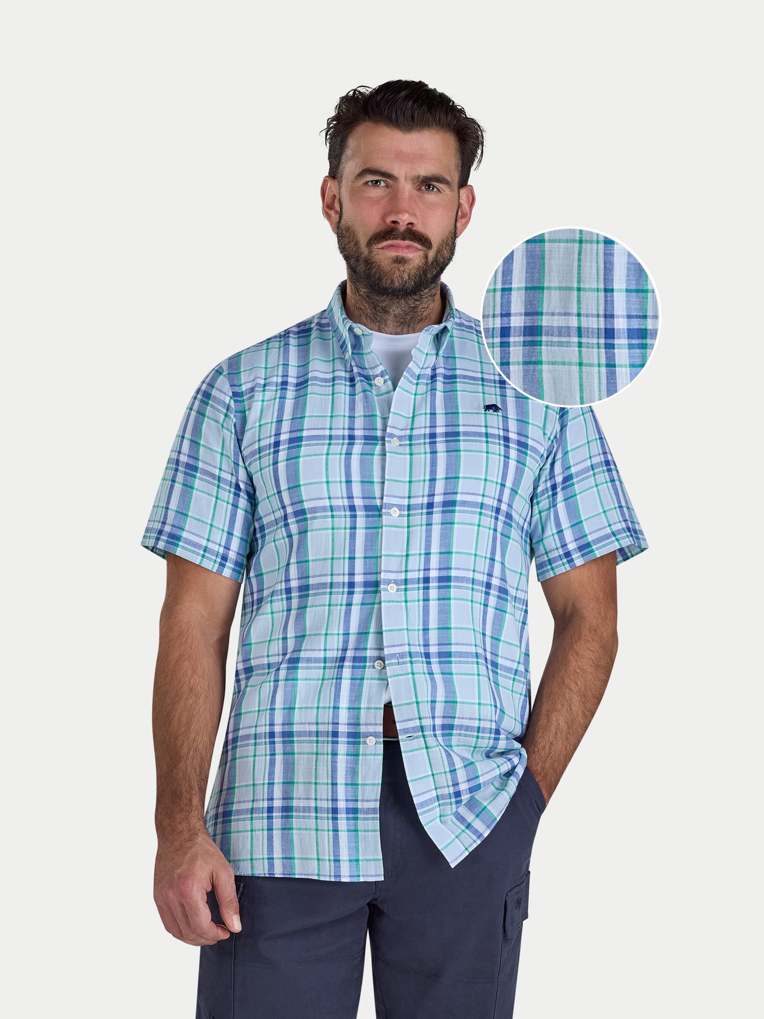Man wearing a blue and green checkered shirt with a close-up of the fabric pattern on a white background.