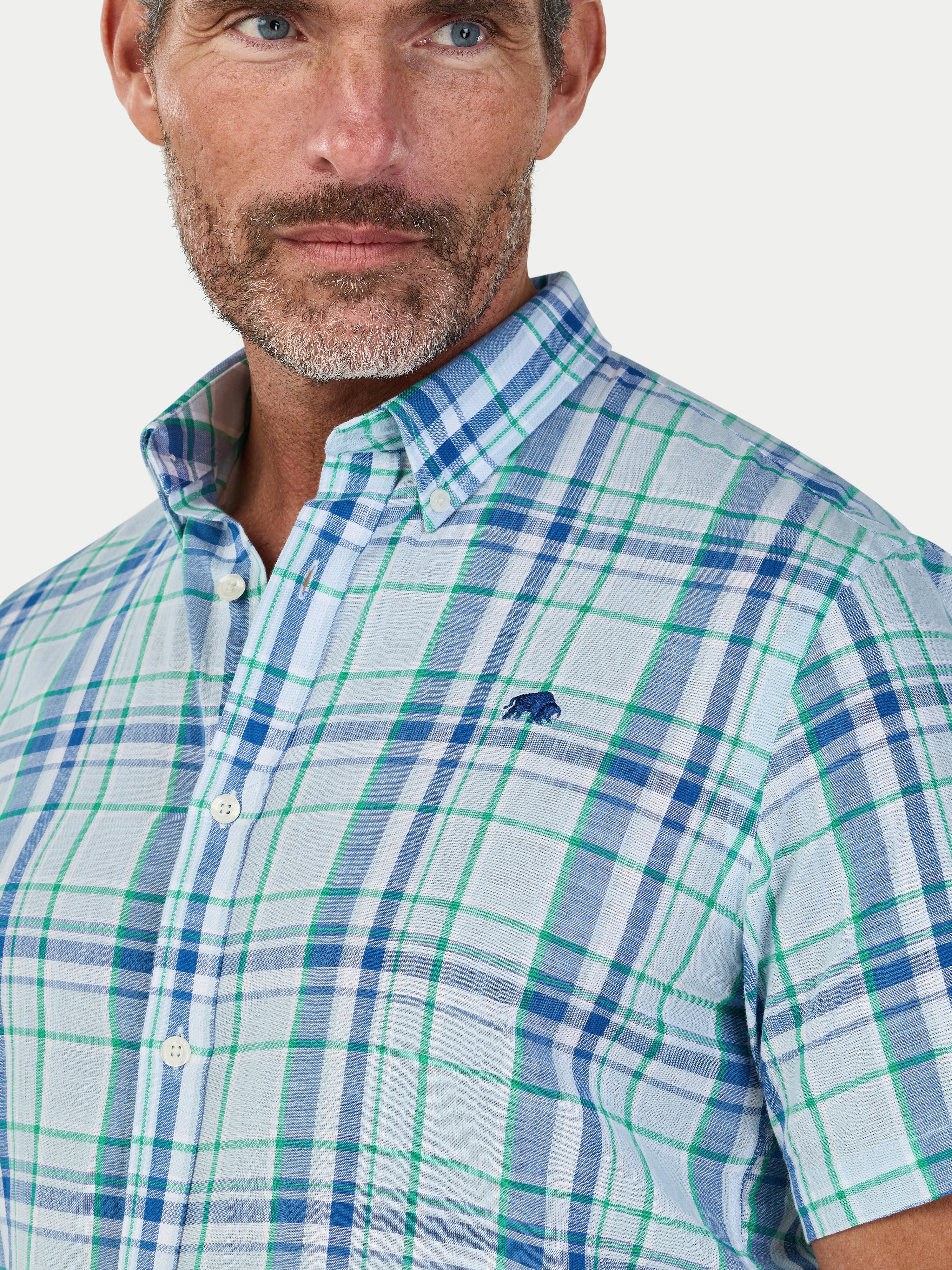 Man wearing a blue and green plaid shirt with a visible brand logo.
