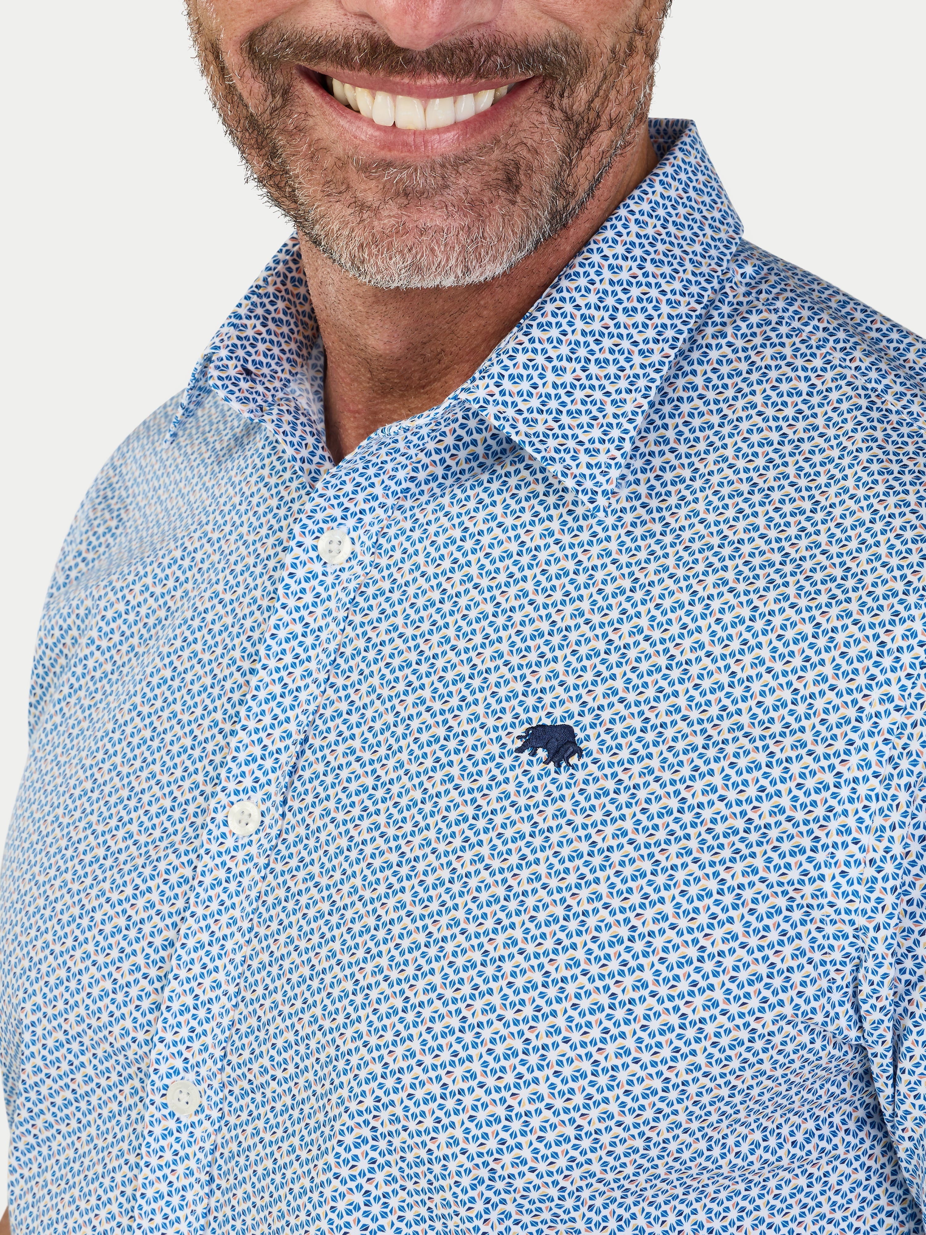 Man wearing a blue patterned shirt with a logo on a white background