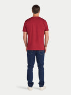 Man wearing a red t-shirt and blue jeans on a white background